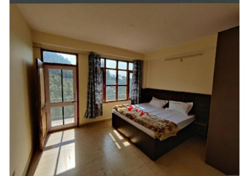 a bedroom with a bed and a large window at Goroomgo Homestay Sukh Dham Shimla - Homestay Like Home Feeling Mountain View in Shimla