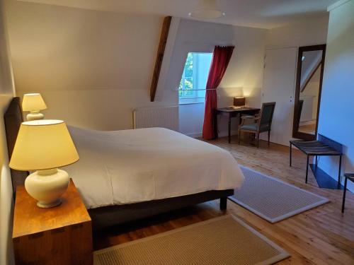 a bedroom with a bed and a table with a lamp at Logis des Tourelles Appartement in Cognac