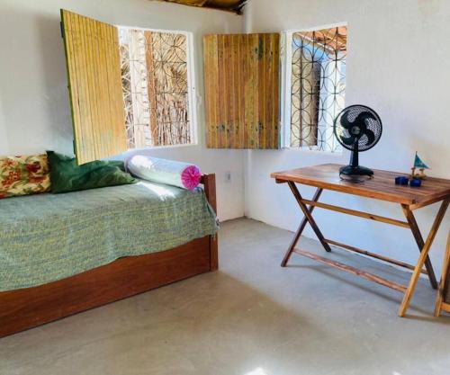 a bedroom with a bed and a desk and windows at Casa Flora Canoa Quebrada in Canoa Quebrada