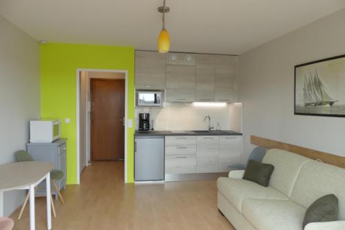 Una cocina y una sala de estar con un sofá y una mesa. en Le Sylvania, en Saint-Georges-de-Didonne