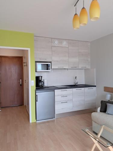 une cuisine avec des armoires blanches et un canapé dans une pièce dans l'établissement Le Sylvania, à Saint-Georges-de-Didonne