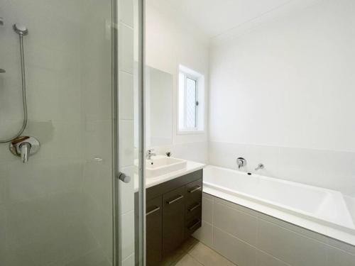 La salle de bains blanche est pourvue d'un lavabo et d'une douche. dans l'établissement New Utopia 4 Bedrooms House near Springfield, à Bellbird Park