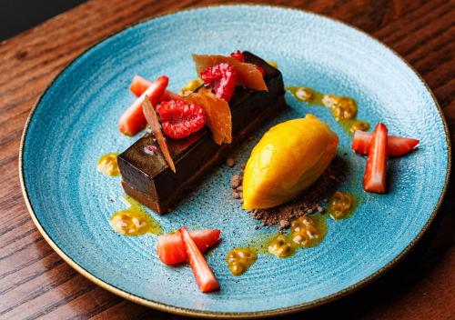a blue plate with a piece of chocolate dessert with fruit at The Prince Akatoki London in London