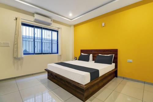 sypialnia z łóżkiem z żółtymi ścianami i oknem w obiekcie OYO Dreams Comforts Lodging and Boarding w mieście Bengaluru