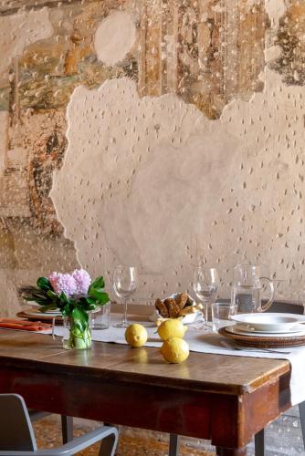 a wooden table with plates and wine glasses on it at Residenza Roccamaggiore in Verona