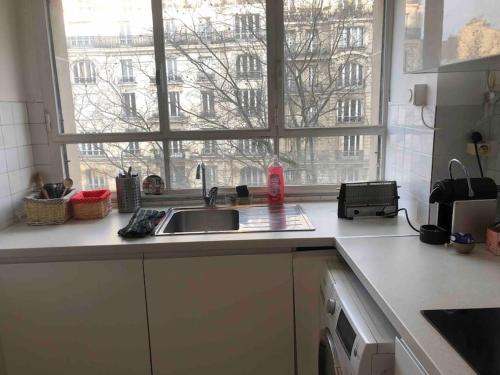 a kitchen counter with a sink and a window at Grand appartement proche métro in Paris