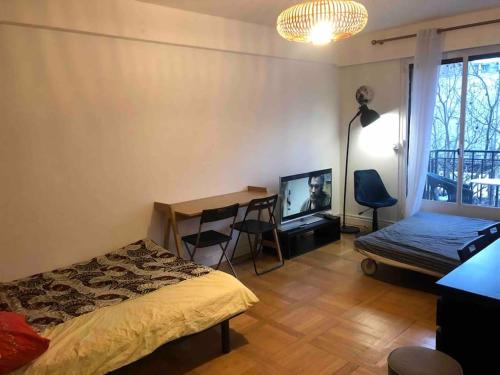 a bedroom with a bed and a desk and a television at Grand appartement proche métro in Paris
