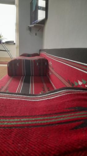 Cama en habitación con manta roja en M.T Apartments en Madaba