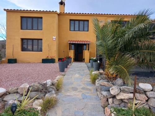 a yellow house with a stone walkway in front of it at Casa rural los Cerezos in Albox