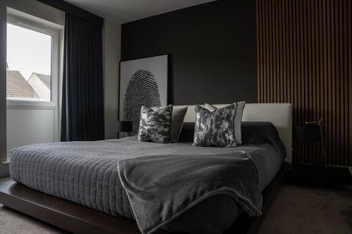 a black bedroom with a bed with pillows and a window at Luxury Worcester Townhouse - Free Parking in Henwick