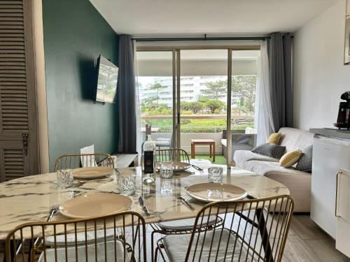 une salle à manger avec une table, des chaises et un canapé dans l'établissement 4 pers , 100m de la plage marina baie des anges French Riviera, à Villeneuve-Loubet