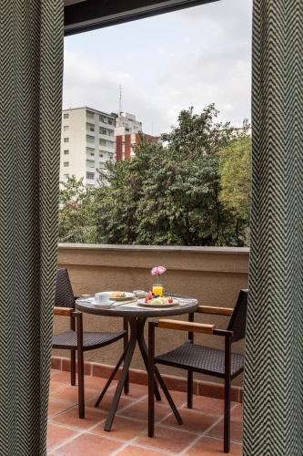 a table and chairs on a balcony with a window at L'Hotel PortoBay São Paulo in Sao Paulo