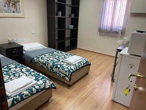 a small room with two beds and a refrigerator at Coral guest house Netanya in Netanya