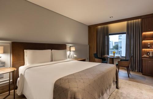a hotel room with a large bed and a desk at L'Hotel PortoBay São Paulo in Sao Paulo