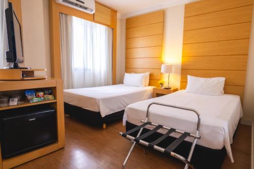 a hotel room with two beds and a flat screen tv at eSuítes Congonhas by Atlantica in Sao Paulo
