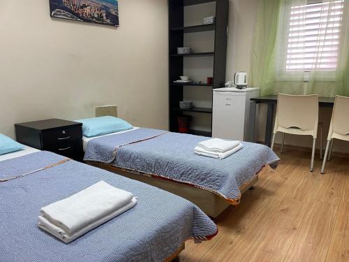a room with two beds and a table and chairs at Coral guest house Netanya in Netanya