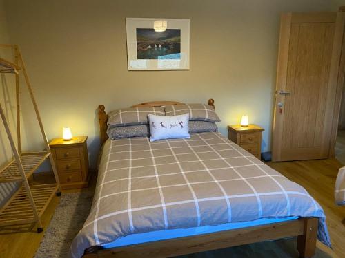 um quarto com uma cama com duas mesas de cabeceira e duas velas em Bellfield. Skeabost bridge em Tole