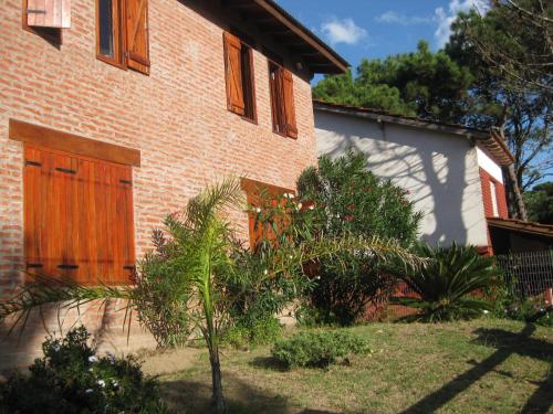 uma casa de tijolos com uma porta de madeira ao lado em La casa del búho em Mar de Ajó