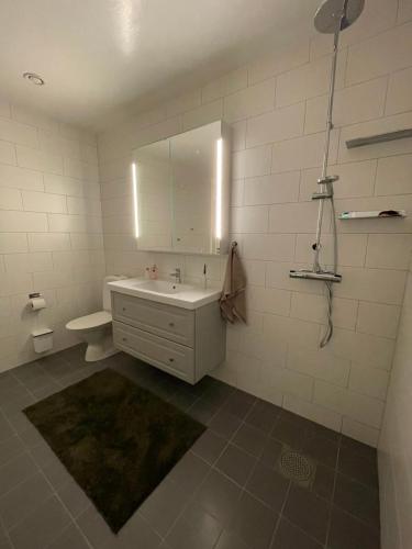 La salle de bains blanche est pourvue d'un lavabo et d'un miroir. dans l'établissement Orrvägen, à Torshälla