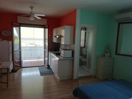 eine Küche mit roten und grünen Wänden und ein Zimmer mit einem Bett in der Unterkunft Holiday by the pool in our cozy flat - Beahost in Bibione