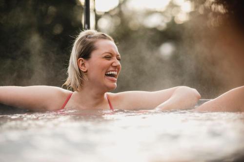 une femme riant dans un bain à remous dans l'établissement Cleeves Cabins Ailsa Lodge with hot tub luxury, à Dalry