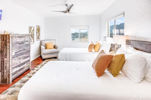 a white bedroom with two beds and a chair at Sundance in the Foothills in Tucson