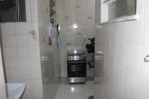 a small white tiled kitchen with a stove in it at Anfitrioca Apartamento Gloria in Rio de Janeiro