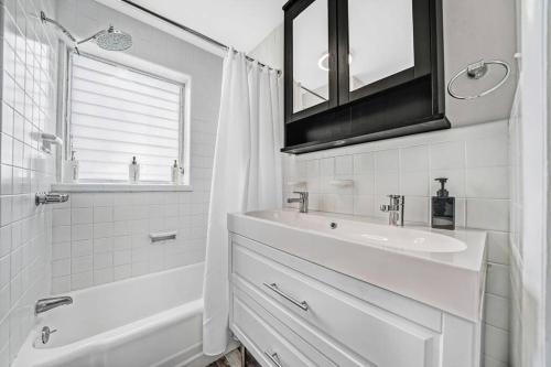 Baño blanco con lavabo y espejo en Modern & Quant KOP 3 Bed/1 ba, en King of Prussia