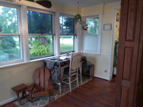 comedor con mesa, sillas y ventanas en Entire Lake Huron sunrise family home with 160 feet of private Beach, en Keewahdin