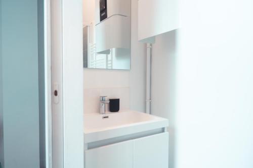 une salle de bain blanche avec un lavabo et un miroir dans l'établissement L'Âme de l'Artiste - Quartier Velpeau, à Tours