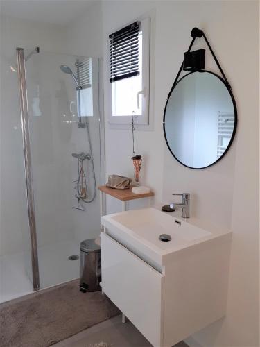 une salle de bain blanche avec un lavabo et un miroir dans l'établissement chez Stéph, à Salles