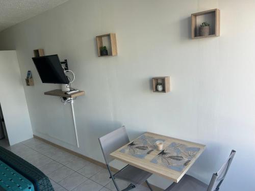 a dining room with a table and a tv on a wall at Studio Cosy Anse Mitan Trois Ilets in Les Trois-Îlets