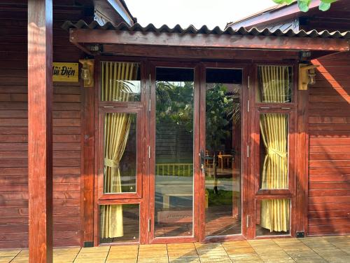 an entrance to a wooden house with glass doors at TRÚ HOUSE in Mỹ Quang