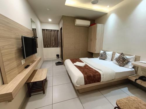 um quarto de hotel com uma cama e uma televisão de ecrã plano em Hotel Kinara em Ahmedabad