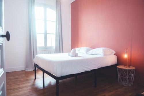 Ce lit se trouve dans une chambre dotée d'un mur rouge. dans l'établissement Le Ronsardien - Appartement calme et confortable, à Tours