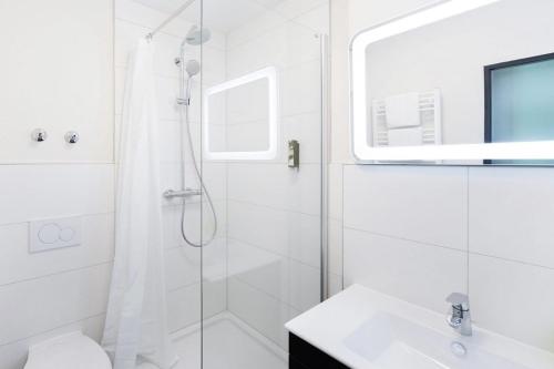 a white bathroom with a shower and a sink at Wildgrün Maxi Lodge 12 in Pfronten