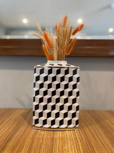 a black and white vase with grass in it on a table at Beautiful Retro Flat above Pub. in Shepton Mallet