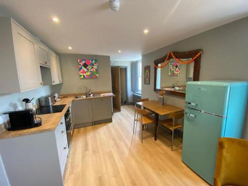 a kitchen with a blue refrigerator and a table at Beautiful Retro Flat above Pub. in Shepton Mallet