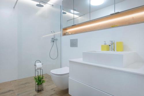a white bathroom with a toilet and a sink at Apartament Premium Sea View PINEA 712 in Pobierowo
