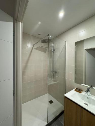 une salle de bain avec une douche en verre et un lavabo dans l'établissement Appart'hotel Le clos des voyageurs - BY PRIMO C0NCIERGERIE, à Sennecey-le-Grand