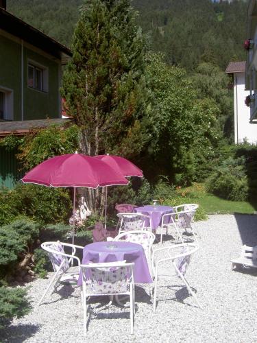 a group of purple tables and chairs with an umbrella at Hotel Garni Hubertus-Nostalgie & Charme in Fulpmes