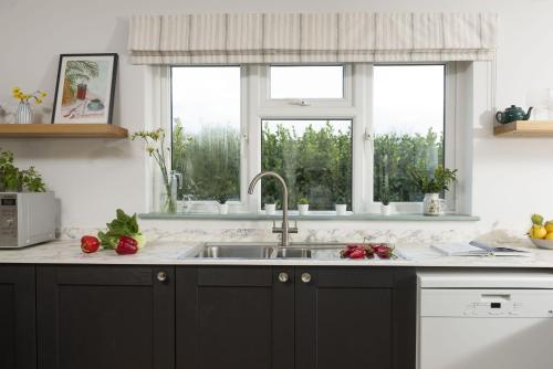 a kitchen with a sink and two windows at Westaway House in Port Isaac