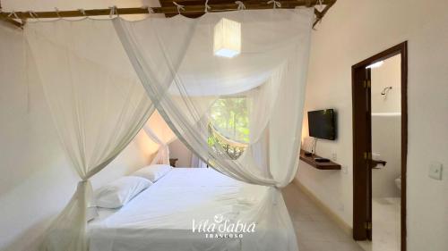 1 dormitorio con cama con dosel y ventana en Pousada Vila Sabiá Trancoso, en Trancoso