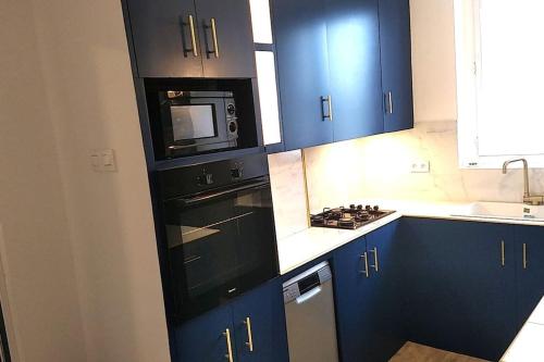 cocina con armarios azules y microondas negro en Appartement une chambre avec balcon, en Chambly