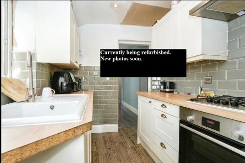 uma cozinha branca com um lavatório e um fogão em 3 bed house in Gloucester near to city centre 