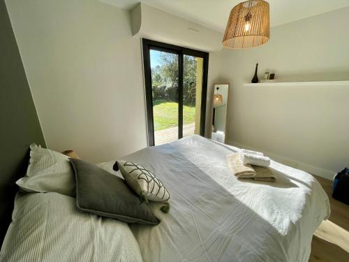 a bedroom with a large white bed with a window at Villa Patio à 800 m de la plage in Seignosse