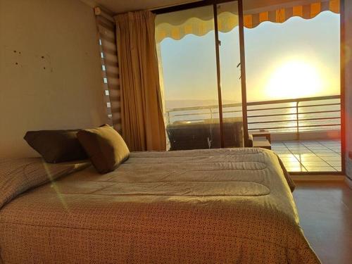 a bedroom with a bed and a large window at Departamento El Encanto - Reñaca in Viña del Mar