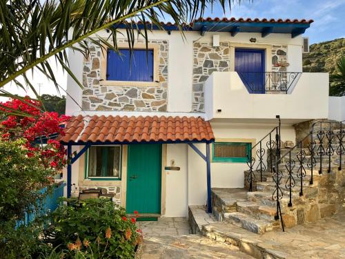 a house with a green door and stairs at Patras Apartments in Fournoi
