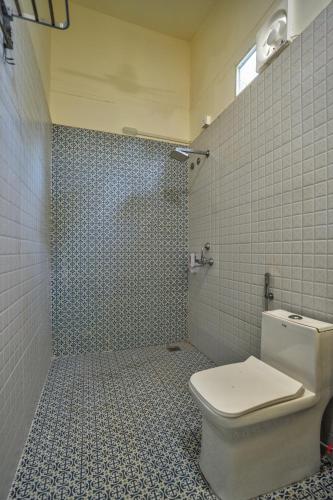 a bathroom with a toilet and a tiled wall at Amore Serenity Resort in Arambol