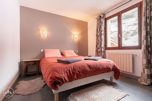 a bedroom with a bed with red sheets and a window at Gîte Le Cembro 6 personnes in Termignon